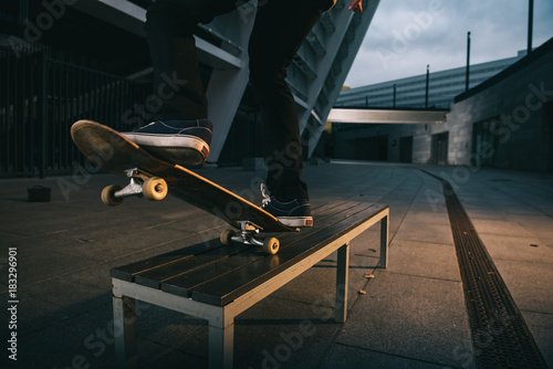 cropped shot of skateboarder balancing with board on bench