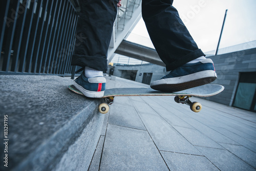 cropped shot of skateboarder balancing on corner of stone wall