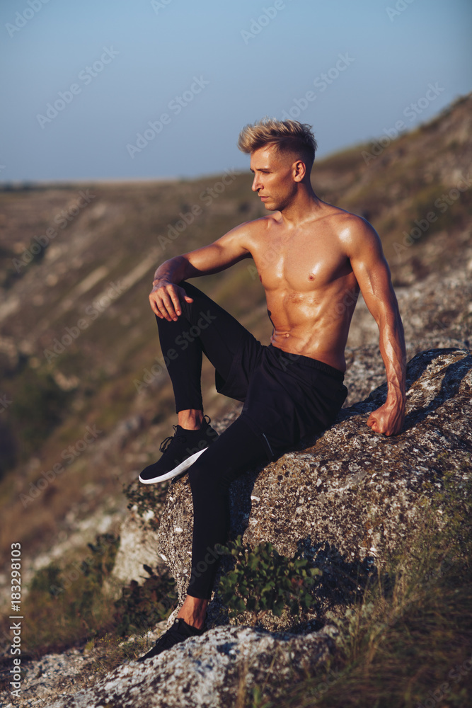 Handsome sportsman posing on rock Handsome sportsman posing on rock