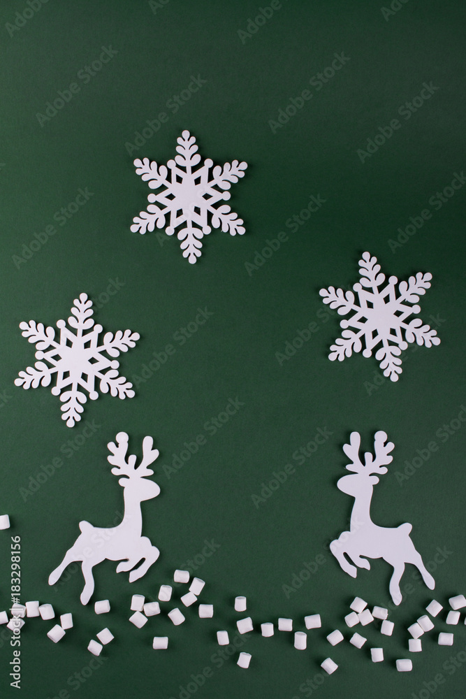 Winter composition with  deers and snowflakes. On green background. Christmas card. Wooden figures