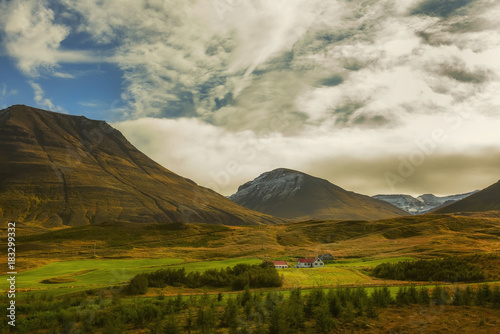 Small houses in the valley among the mountains. Typical Icelandic landscape. A beautiful view of secluded housing. 