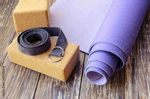 Yoga accessories background, lilac yoga mat, two  cork  blocks and yoga belt. Yogi essentials for practice