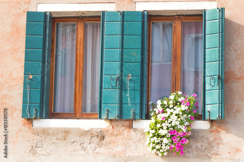 Window with open wooden shutters  decorated with fresh flowers in summer time  open window in rural house europe style.