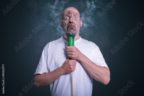 Mann mit grüner explodierter Silvester Rakete macht dummes Gesicht