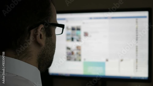 A man using on social networks. Businessman reads the news. Computer monitor showing blur Facebook news feed page young girl online. photo