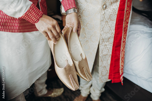 Indian groomsman holds golden shoes for a Hindu groom