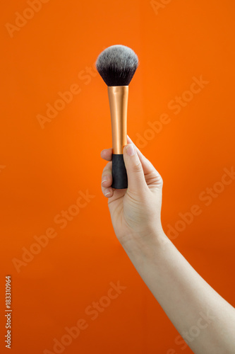 Set of makeup brushes on orange background.