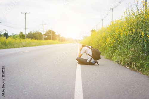 Fotografie depress and hopeless , Travel hitchhiker man with backpack sitting on roadside,