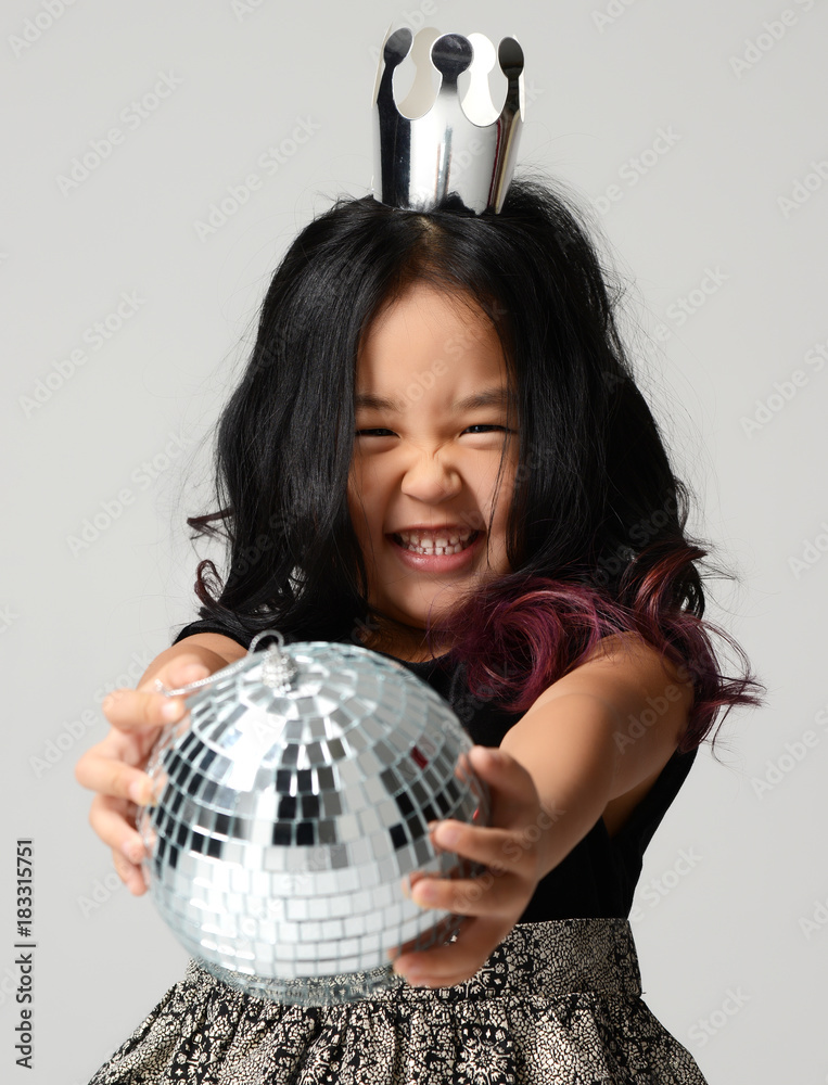 Young happy asian girl kid smiling in silver crown and give away disco ball decoration Young happy asian girl kid smiling in silver crown and give away disco ball decoration
