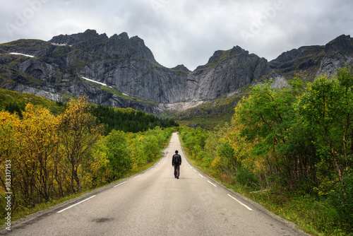 Hiker walks on a scenic road on Lofoten islands in Norway