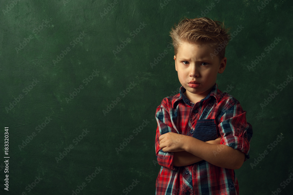 Sad confused little boy stands in dark corner and is afraid of something, copyspace