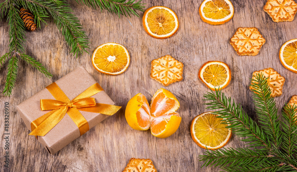 Christmas decorations with fir tree, gift box, cookies, snowflakes and tangerine. Gift box with golden bow. Christmas decorations with fir tree, gift box, cookies, snowflakes and tangerine. Gift box with golden bow.