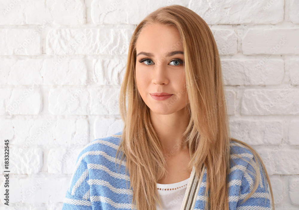 Portrait of beautiful young woman against brick wall