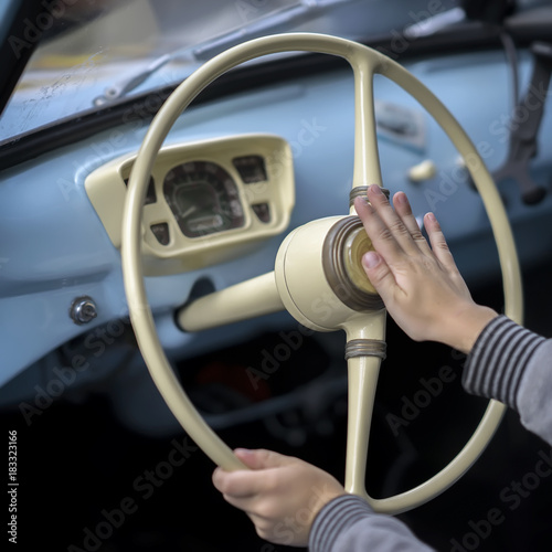 Close-up of hands of boy at the steering wheelof the retro car his great-great-grandfather, testing beeping, sound signal