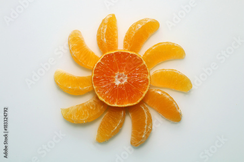 Slices of mandarin lined in the form of the sun on a white background