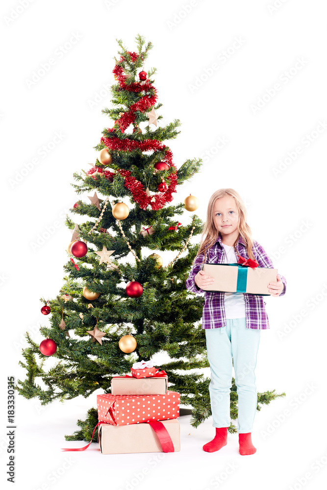 Portrait of little girl standing near Christmas tree with gift box in her hands on white background Portrait of little girl standing near Christmas tree with gift box in her hands on white background