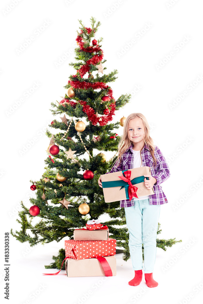 Portrait of little girl standing near Christmas tree with gift box in her hands on white background Portrait of little girl standing near Christmas tree with gift box in her hands on white background
