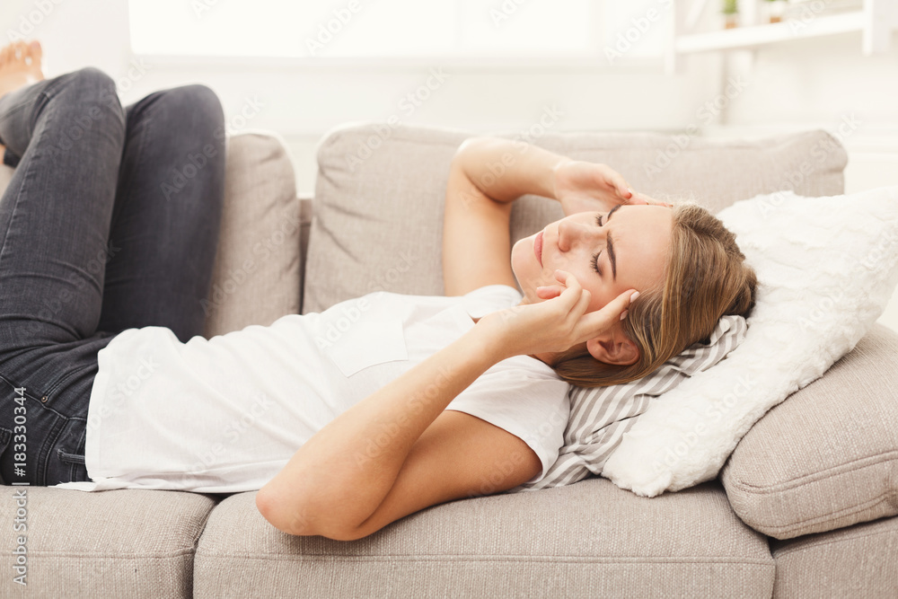 Casual blonde girl feeling pain while lying on the couch Casual blonde girl feeling pain while lying on the couch
