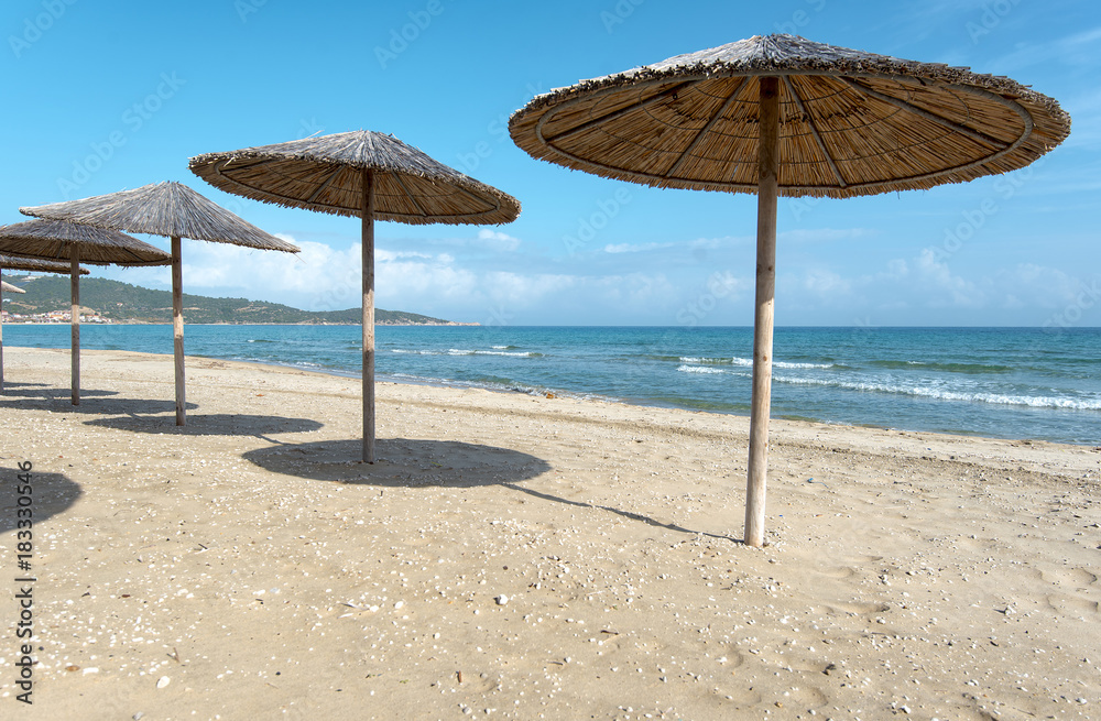 Sarty, Greece, Summer beach without people, sea and sand, empty sea and beach background with straw umbrellas