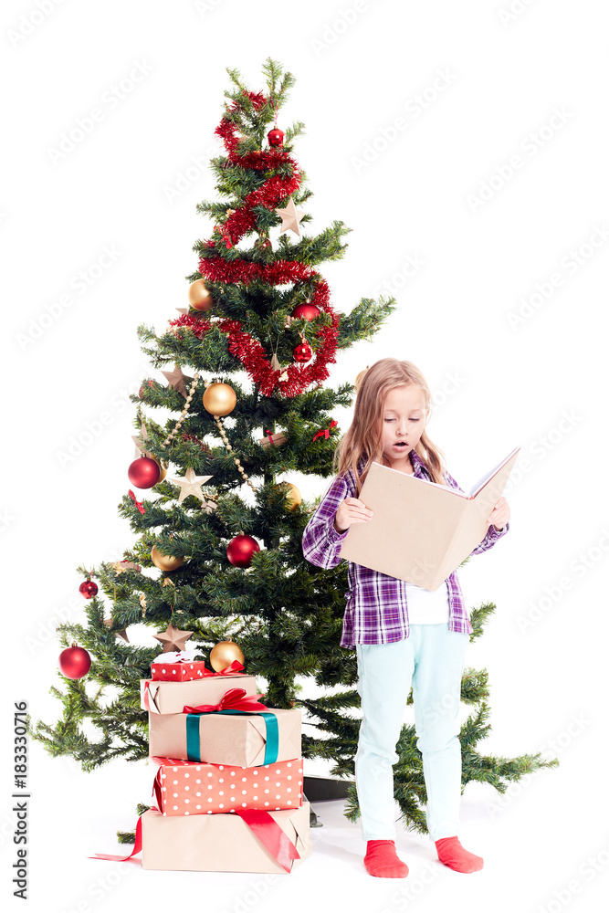 Portrait of cute little girl reading book near Christmas tree on white background Portrait of cute little girl reading book near Christmas tree on white background