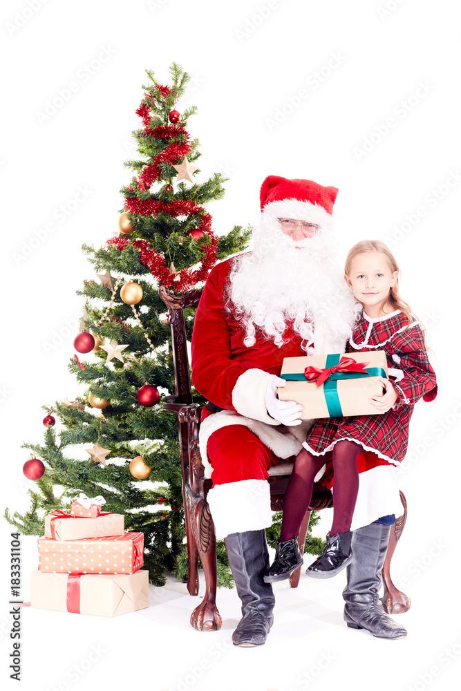 Cute little girl receiving gift from Santa Claus sitting on his lap near Christmas tree Cute little girl receiving gift from Santa Claus sitting on his lap near Christmas tree