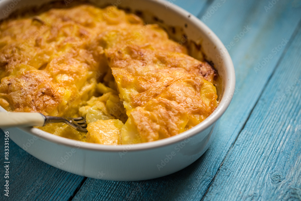 potato gratin with cream and Parmesan cheese on a blue background potato gratin with cream and Parmesan cheese on a blue background