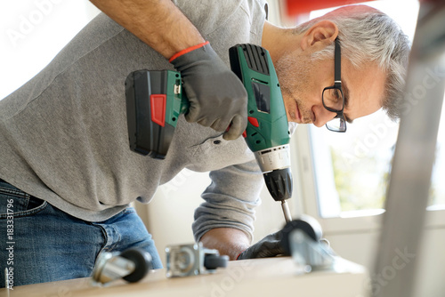 Wallpaper Mural Man assembling DIY furniture using electric drill Torontodigital.ca