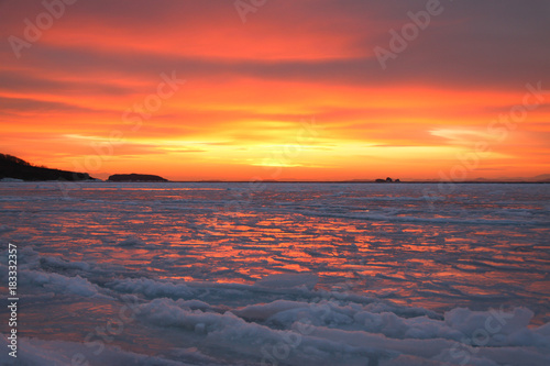 The sea is covered with ice at sunset.