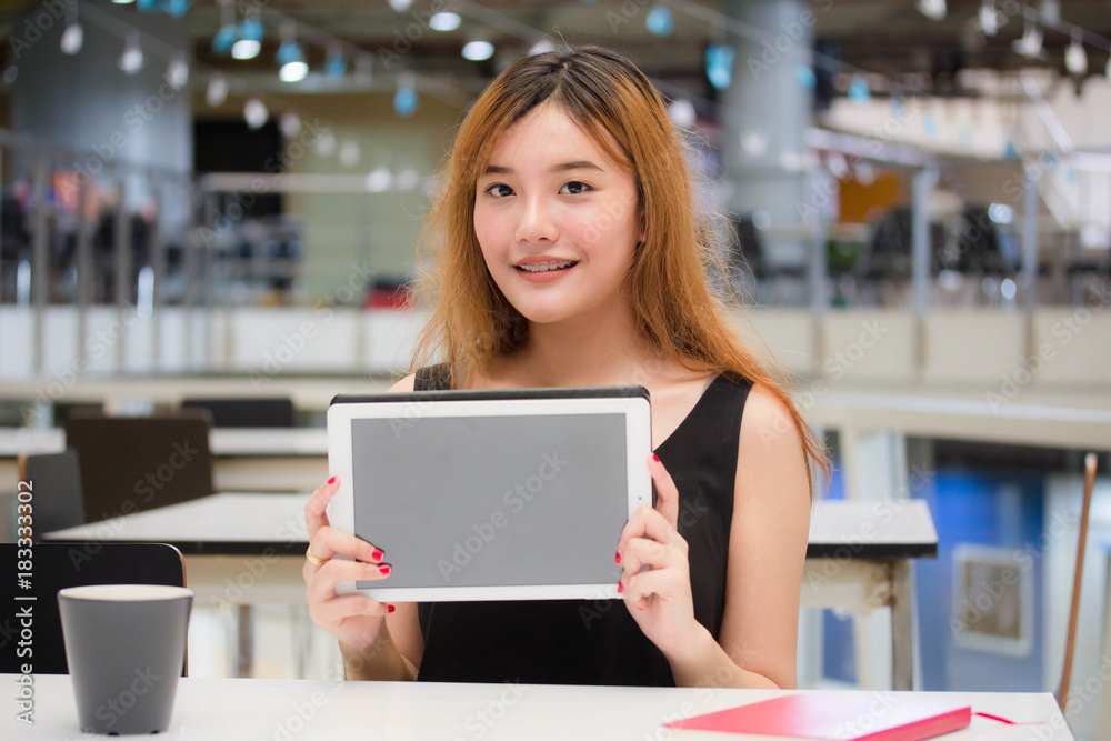 Beautiful young adult thai chinese bronze hair show her tablet.