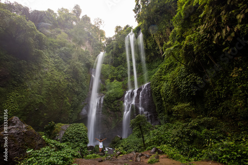 Woman in white dress at the Sekumpul waterfalls in jungles on Bali island  Indonesia