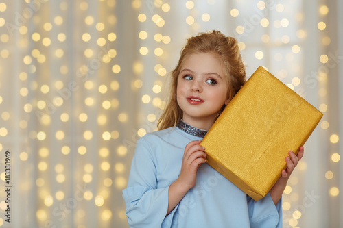 Little cute girl in blue dress with a christmas present
