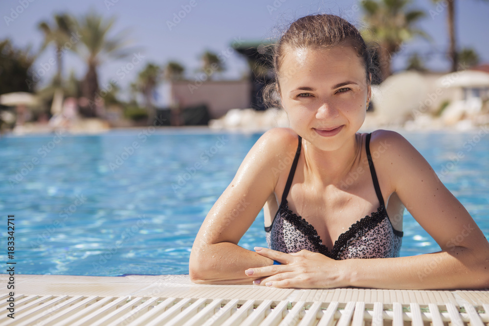 Beautiful ordinary simple fit slim caucasian brunette woman in swimsuit in a swimming pool on a vacaion in tropical country near sea. Hot sunny weather, noon Beautiful ordinary simple fit slim caucasian brunette woman in swimsuit in a swimming pool on a vacaion in tropical country near sea. Hot sunny weather, noon