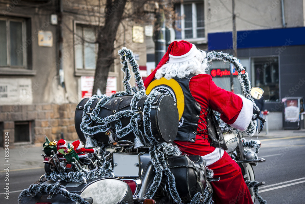 a man dressed in a Santa costume drives a motorcycle and hasten to leave presents to obedient children. Santa Claus as a rocker.a lightly blown-up rocker with red clothes and a hat instead of a helmet a man dressed in a Santa costume drives a motorcycle and hasten to leave presents to obedient children. Santa Claus as a rocker.a lightly blown-up rocker with red clothes and a hat instead of a helmet