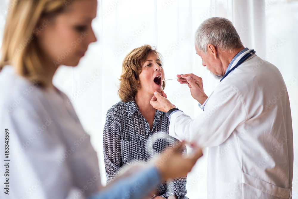 Язык врачей по фото Senior doctor examining a senior woman in office. фотография Stock Adobe Stock