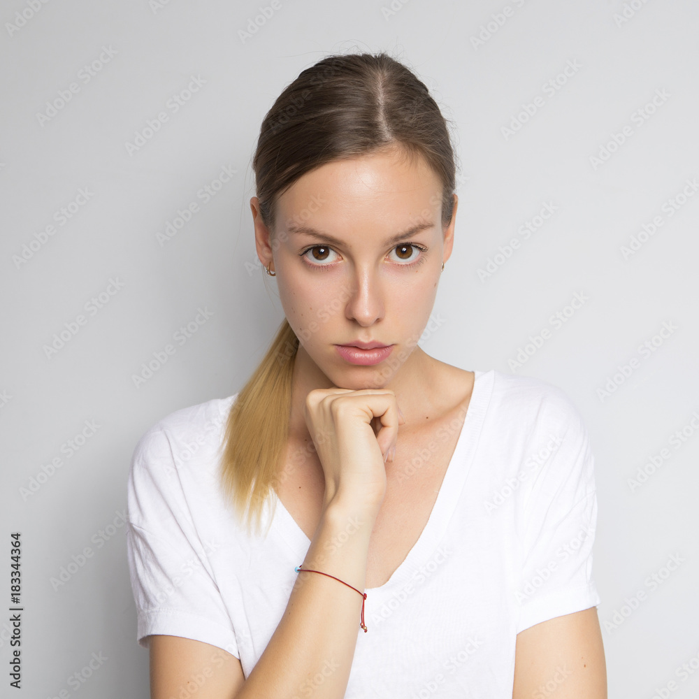 Beautiful brunette caucasian woman in white blouse with bright emotions standing on a neutral grey background. Her hands make a gesture. She thoughtful Beautiful brunette caucasian woman in white blouse with bright emotions standing on a neutral grey background. Her hands make a gesture. She thoughtful