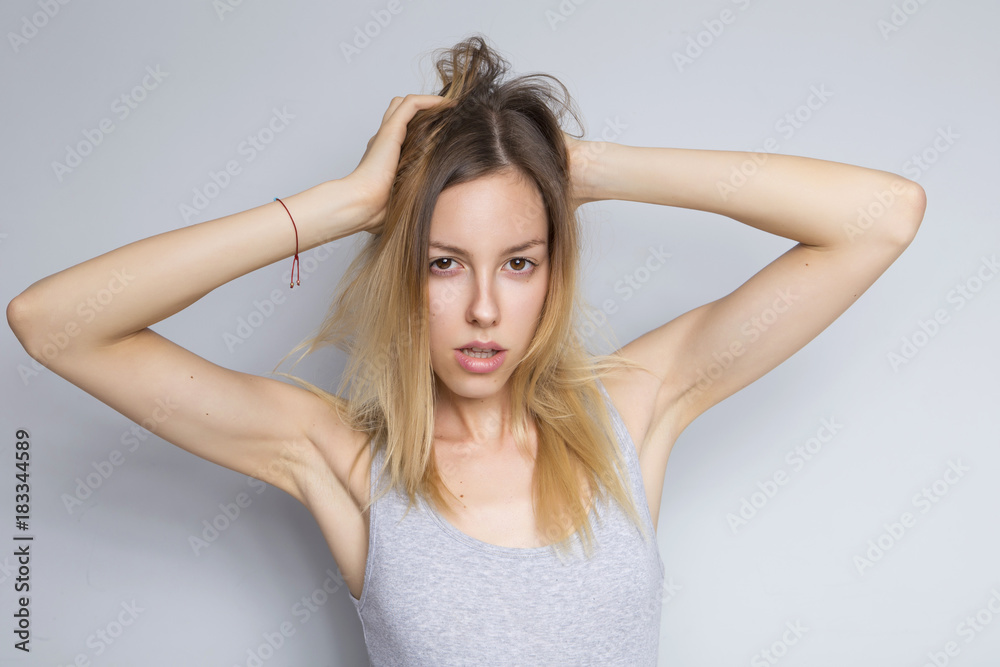 Beautiful brunette caucasian woman in grey blouse with bright emotions standing on a neutral grey background. Her hands make a gesture. She act sexy, seductive Beautiful brunette caucasian woman in grey blouse with bright emotions standing on a neutral grey background. Her hands make a gesture. She act sexy, seductive