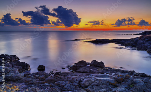Beautiful sunrise on rocky shore and dramatic sky clouds