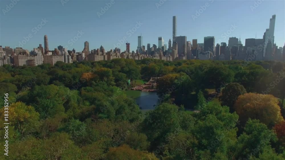 Aerial shot of New York Central Park, camera moving backwards over it, city view behind the trees. Concept of a green zone in a city. Aerial shot of New York Central Park, camera moving backwards over it, city view behind the trees. Concept of a green zone in a city.