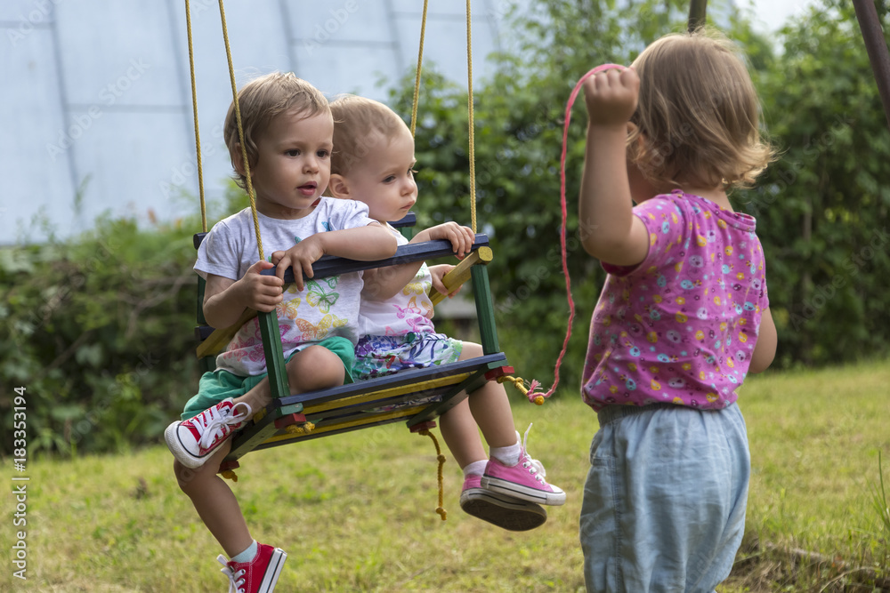 An older sister is swinging her two younger sister