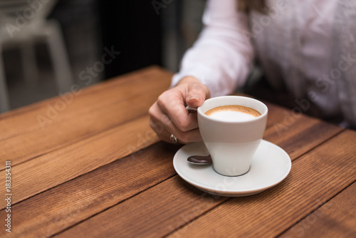 Woman s hand holding coffee cup on wooden table.