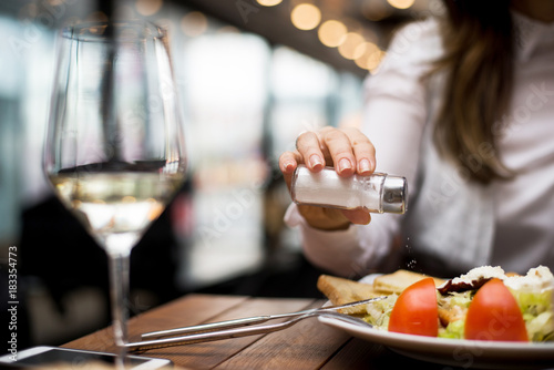 Fotografie Woman adding salt to food in restaurant.