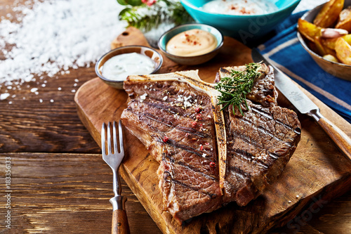 Piece of barbecued t-bone steak on wooden board photo