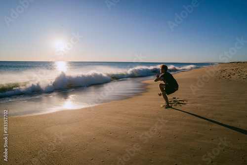 Man doing Yoga at sunset on a beach in Portugal