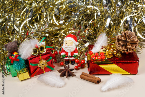 Figurine de Père Noël et paquet cadeau devant une guirlande dorée