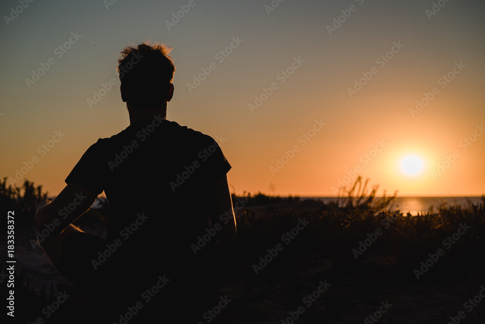 Man watching the sunset with hands up in Portugal