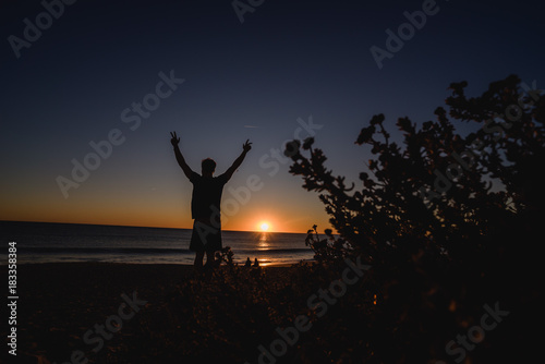 Man watching the sunset with hands up in Portugal