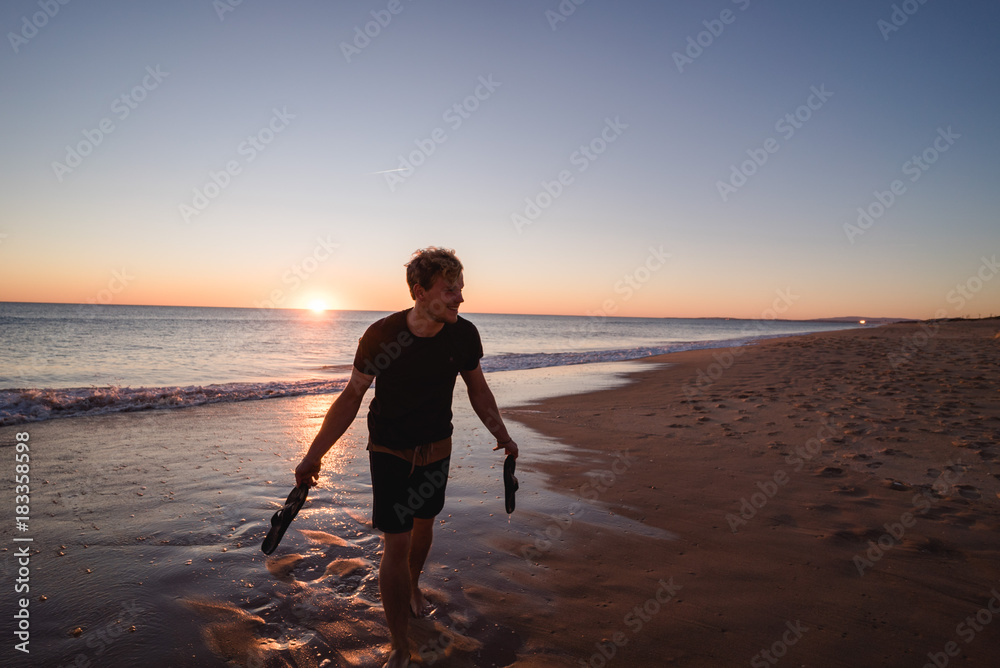 Man walking on the beach with shoes in his hands in Portugal