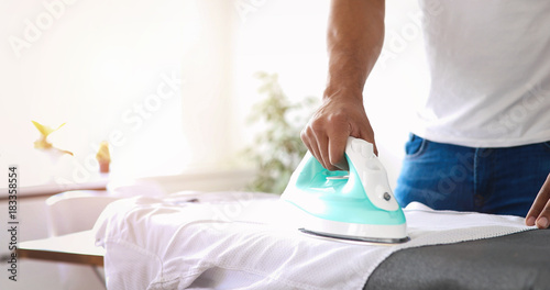 Tablou canvas Man ironing shirt on ironing board
