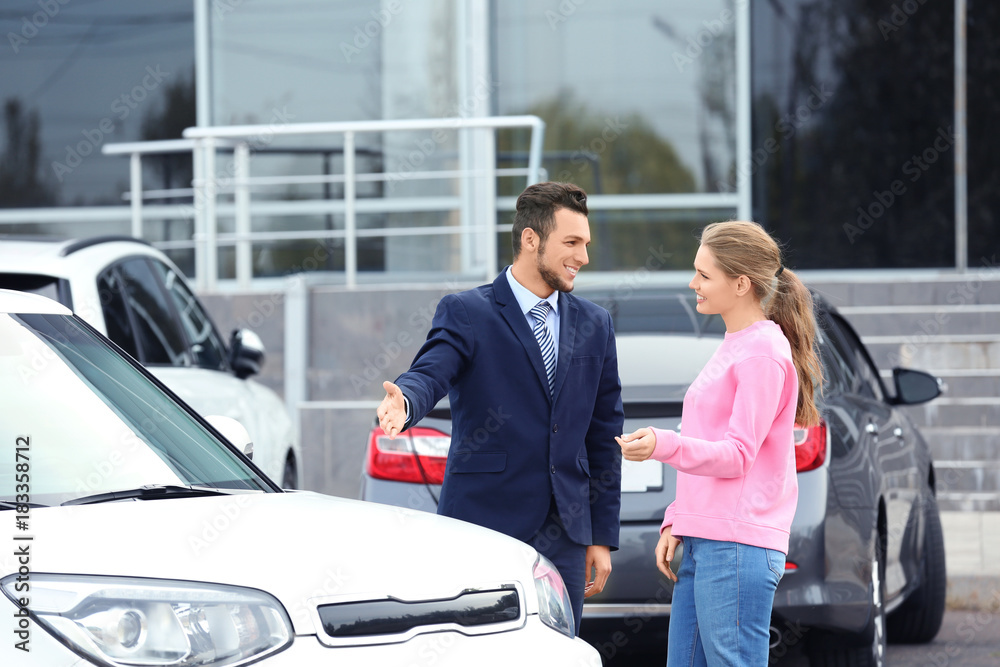 Salesman showing new car to customer outdoors