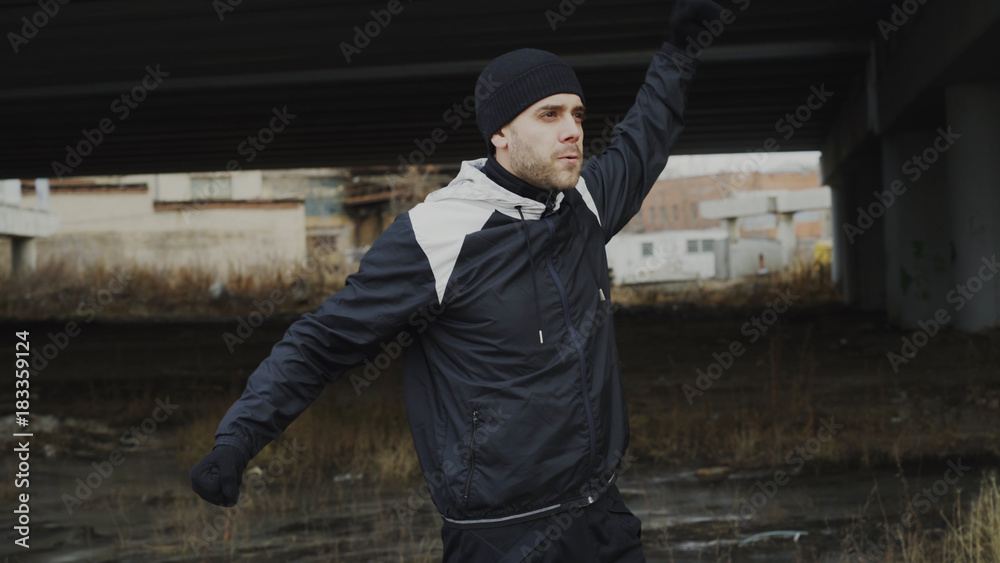 Attractive athlete man warming up before workout training at urban location outdoors in winter season